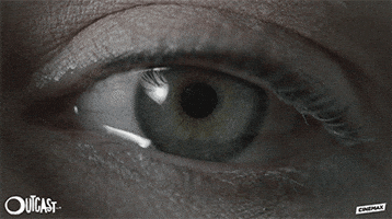 TV gif. A scene from the Outcast. A close up of a blue eye that blinks and tears leak out. 