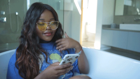 Micro-influencer Black girl with yellow shades flipping hair and on her phone