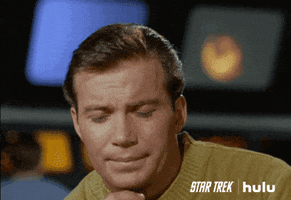 TV gif. Looking thoughtful, William Shatner as Captain Kirk in Star Trek rubs his chin as if he is considering something.