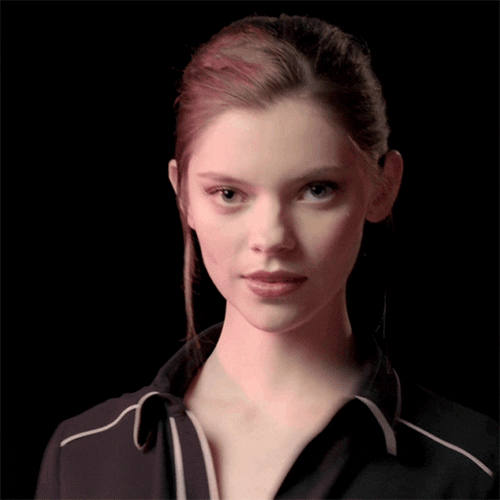 Video gif. A woman twists her shoulder as she gives a wink and a smile towards us. 