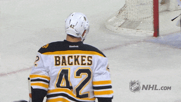 Sports gif. David Backes from the Boston Bruins hockey team high fives one of his fellow players on the rink, before the two and another player join in for a celebratory hug.