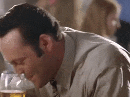 Movie gif. Vince Vaughn as Jeremy in Wedding Crashers. He is chortling at the table, laughing with his mouth full and throwing his head back in utter glee.