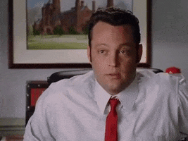 Movie gif. Vince Vaughn as Jeremy in Wedding Crashers sits in an office chair looking off screen with anticipation. Then he throws his arms up, grits his teeth, and says, "Yes!" like he's celebrating. 