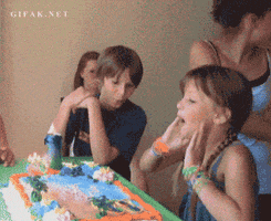 Video gif. Right after she blows out a candle on a birthday cake, girl gets her head pushed into the cake by an older girl behind her.