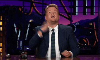TV gif. James Cordon on The Late Late Show. He rolls his hand in a 360 motion and gives us a bow while sitting at the table.