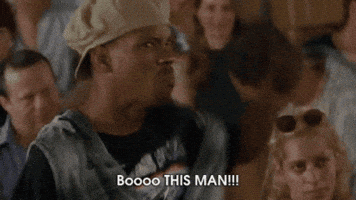 Movie gif. A scene from Half Baked. A man stands with a disgruntled looking crowd sitting behind him. He points angrily as if offended at someone, saying., “Boo this man! Boo!” He then grabs the hat off of his head and chucks it. The crowd behind him starts to get up and follow his protest.