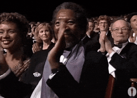 Celebrity gif. Morgan Freeman sits amongst a crowd at an award show. He looks up at the stage with admiration and a wide smile spread across his face. He gives big, strong claps to signify how proud he is. 