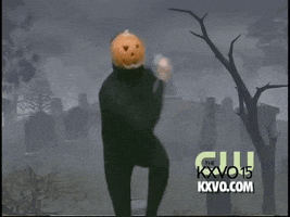 Video gif. Pumpkin Dance man in a black unitard with a jack-o-lantern on his head does dances from side-to-side in front of a graveyard backdrop. 