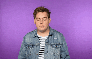 Video gif. A young man sighs, grabbing his brow, covering his face, an exasperated face palm.