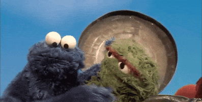 Sesame Street gif. Cookie Monster leans into Oscar the Grouch and hugs him.
