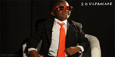 Video gif. YouTube star Kid President wears a suit with matching orange tie and sunglasses. He leans toward his arm to remove his cool shades.