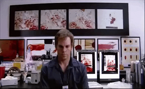 Michael C Hall as Dexter Morgan, a forensic scientist blood splatter analyst,  sitting at desk spinning in his chair.