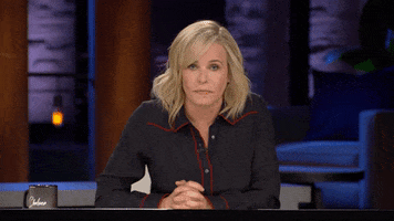 TV gif. Leaning forward at her desk on her talk show, Chelsea Handler takes a deep breath and sighs in frustration.