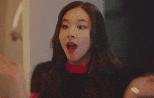 Video gif. Chaeyoung from the k-pop band Twice claps both of her hands on her cheeks, with an energetic, excited expression. 