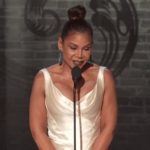 Celebrity gif. Daphne Rubin-Vega at the Tony Awards. She pouts her lips sassily and raises her hand.