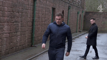 TV gif. Jamie Lomas as Warren and Maxim Baldry as Liam face off in an argument set in an alleyway.