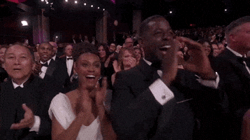 Celebrity gif. Sterling K. Brown and Ryan Michelle Bathe stands up in their chairs at the Academy Awards and clap enthusiastically.