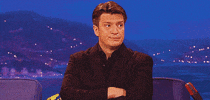 Celebrity gif. Nathan Fillion sits for a late night interview, shaking his head with a stern facial expression.