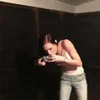 Video gif. Girl shotguns a beer can, but the top hole is open and leaking out beer. She spits the beer out, leans over, and then falls onto the ground.