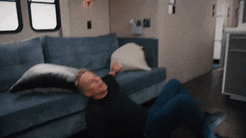 Reality TV gif. A man tries to steady himself against a couch while seated on the floor. Text, "Oh my."