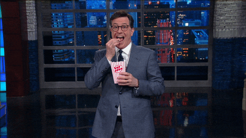Stephen Colbert eating popcorn and grinning