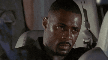 TV gif. Idris Elba as Russell, Stringer Bell from The Wire sits in the back seat of a minivan, looking pensive and perhaps suspicious at someone in the front seat. He then looks away.