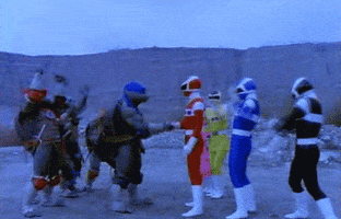 TV gif. In Power Rangers in Space, the Power Rangers meet the Teenage Mutant Ninja Turtles in a desolate landscape. The red Power Ranger, Jason Lee Scott, shakes Leonardo's hand while both crews jump and pump their fists in celebration.