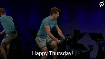 Video gif. Though the rest of the room is dark, a man riding an exercise bike in a blue t-shirt and shorts is lit clearly. He swings his head toward us emphatically to exclaim: Text, "Happy Thursday!"