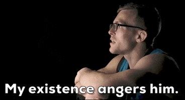 Video gif. Brad Katona, a coach on The Ultimate Fighter, in profile against a black background. He has his arms folded on a surface and is talking to someone offscreen in a matter of fact manner. Text, "My existence angers me."