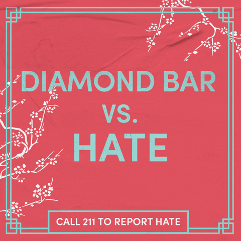 Text gif. Sage green letters on a coral background, surrounded by swaying cherry blossom branches as a butterfly glides through. Text, "Diamond Bar vs hate, call 211 to report hate."