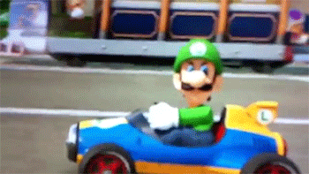 Video game gif. Luigi angrily glares at someone while driving along in his blue and yellow kart.