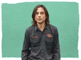 Celebrity gif. Brian Bell of Weezer pulls his arms across his stomach, protecting himself and looking around nervously. Text, "Yikes!"
