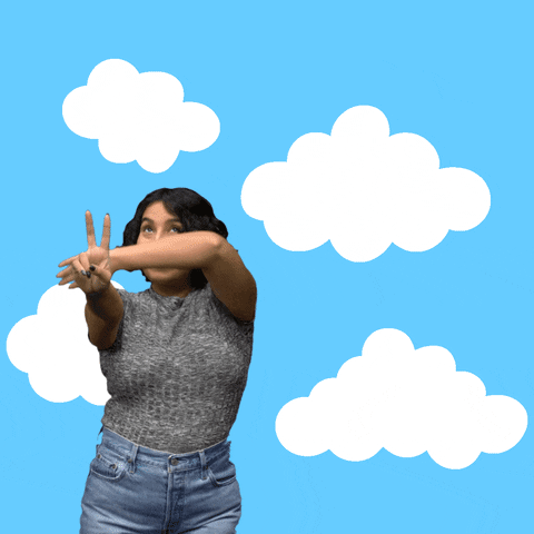 Video gif. Woman smiles as she holds up a peace sign against a sky blue background with drifting clouds. She fans out her opposite arm, revealing an illustrated rainbow that reads, "Imagine peace," then erases it as her arm arcs back over her head.
