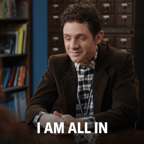 TV gif. Jacob Hill as Jacob in "Abbott Elementary" sits at a table and swoops his hands out in an energetic gesture saying, "I am all in!'
