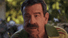 Video gif. An older man is chewing something very slowly and musing about how he feels about the food. He continues to chew and looks at us straight in the eye while saying, "Tastes like paint. And wood."