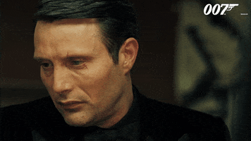 Movie gif. Mads Mikkelsen as Le Chiffre in Casino Royale. He's looking away as he says, "Oops," but quickly turns his head to face the person he's speaking to and smiles sinisterly afterwards.