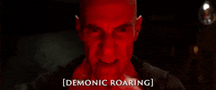 Movie gif. From the Foo Fighters movie Studio 666: An angry red-faced evil demon takes a deep breath and screams. Text, “Demonic Roaring.”