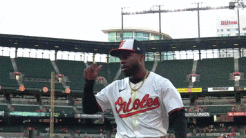 Sports gif. Cedric Mullins of the Baltimore Orioles tips his cap as he moves through a stadium in slow motion.