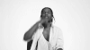 Celebrity gif. Black and white frame showing A$AP Rocky looks up, crossing his chest and then kissing his fingers and raising up heavenward.