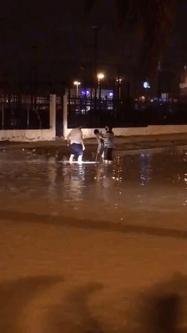 Men Wade Through Floodwaters in Kuwait City