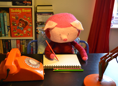 Stop motion gif. A stuffed pig is sitting at a table writing in a notebook. It looks very studious as its head tips back and forth in concentration.