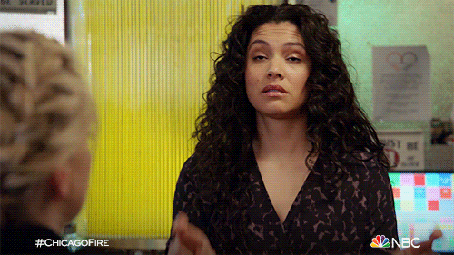 TV gif. Miranda Rae Mayo as Stella Kidd on Chicago Fire crosses her fingers on both hands.