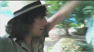 Video gif. A man twirls around with his arms up in the air. 