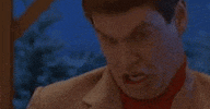 Movie gif. Jim Carey as Lloyd in "Dumb and Dumber" makes an absurd retching facial expression and gesture, bucking his neck forward and curling his lips over his teeth and then clenching his jaw.