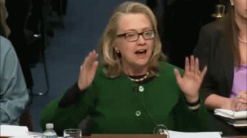 Political gif. Dressed in an emerald green button up dress, Hillary Clinton passionately speaks with her hands and pounds her fists against the table to really get her message across.