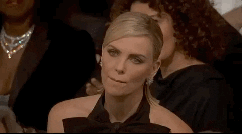 Celebrity gif. Actress Charlize Theron sits in the audience at the Golden Globes. She nods her head like she's amazed and sucks on her lips, a little annoyed by something just said.