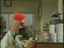 TV gif. A fire erupts out of a wire basket in a lab and Beaker from the Muppets pops up in panic. He looks around frantically, his mouth open agape, and his muppet arms flailing around.