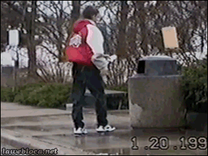 Video gif. Man throws trash into a trash can and an orange cat pops out. He jumps back in shock as another black cat jumps out of the trash can, and runs off.