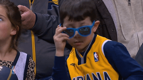 Sports gif. A kid wearing Indiana Pacers gear takes off his sunglasses and points at us.