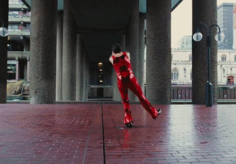 Harry styles in red jumpsuit leaping in dance